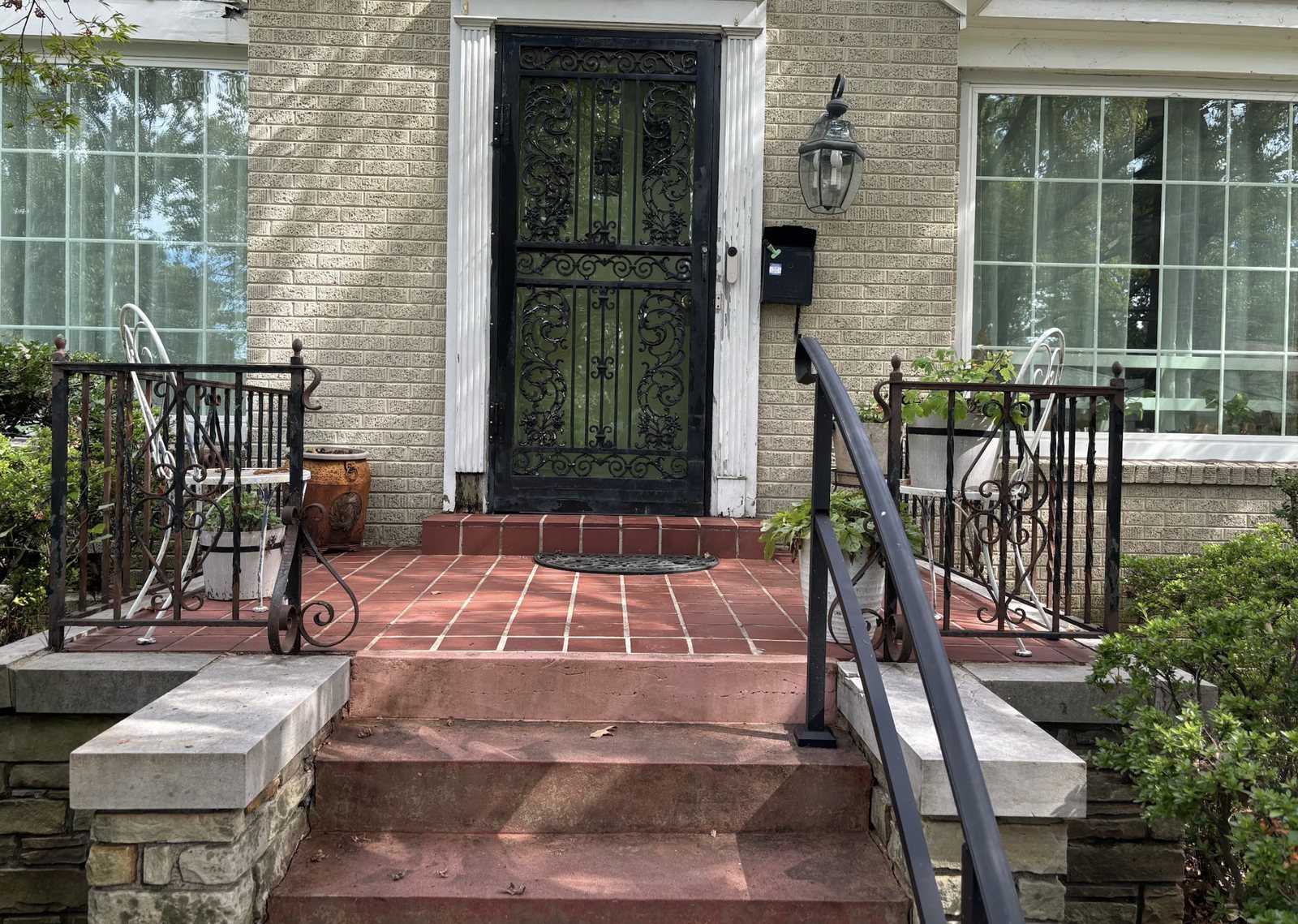 Brick home exterior with painted trim, black iron storm door and front steps